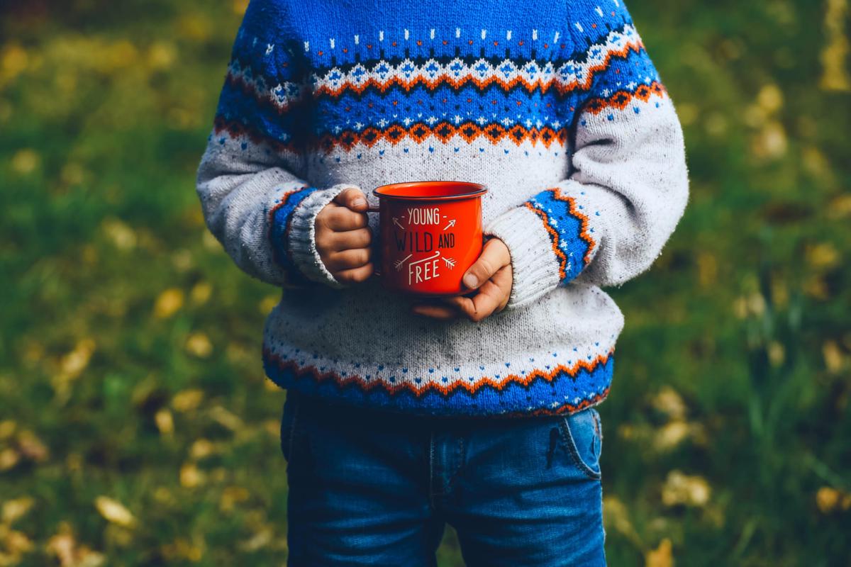 A boy holding a nice red mug.